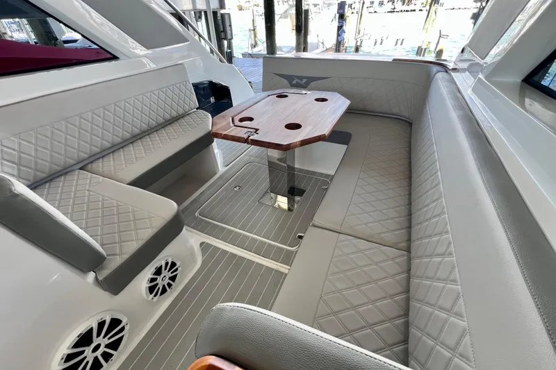 Slide: The Image of Luxurious seating area on 2024 NX Boats 370 HT with elegant quilted upholstery and wooden table. - 27