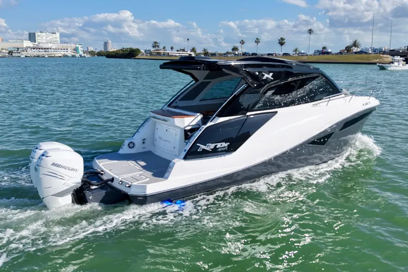 Slide: The Image of 2024 NX Boats 370 HT cruising in a marina with waterfront buildings in the background. - 3