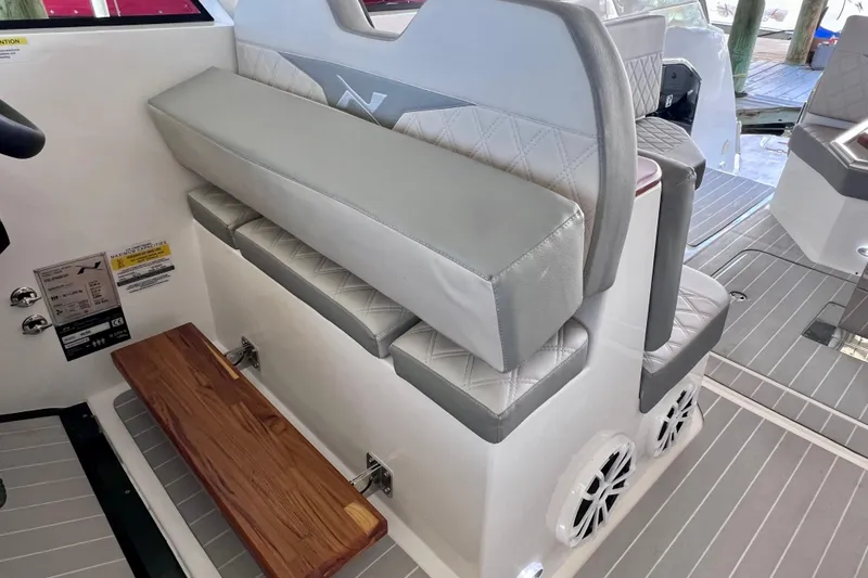 Slide: The Image of 2024 NX Boats 370 HT interior seating with gray cushions and wooden footrest. - 32