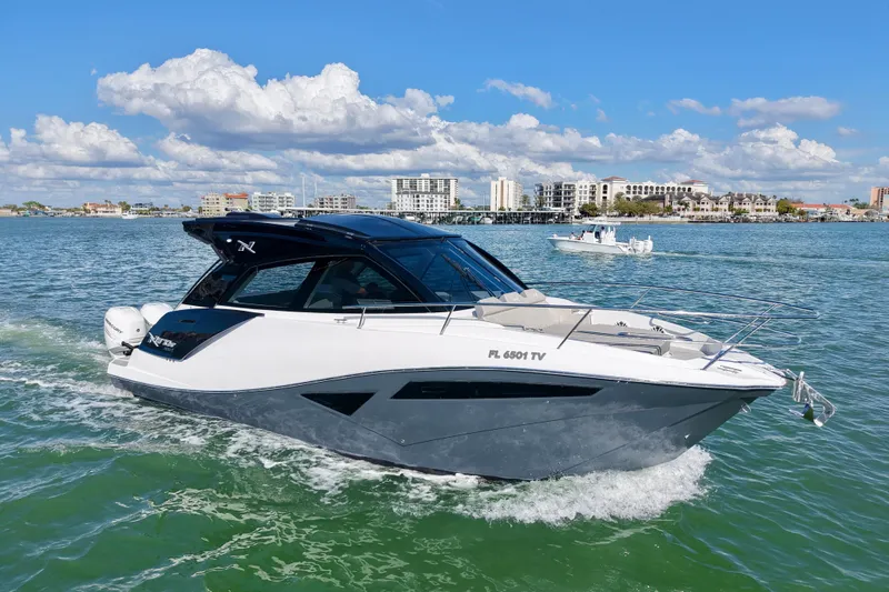 Slide: The Image of 2024 NX Boats 370 HT cruising on a sunny day with cityscape in background. - 5