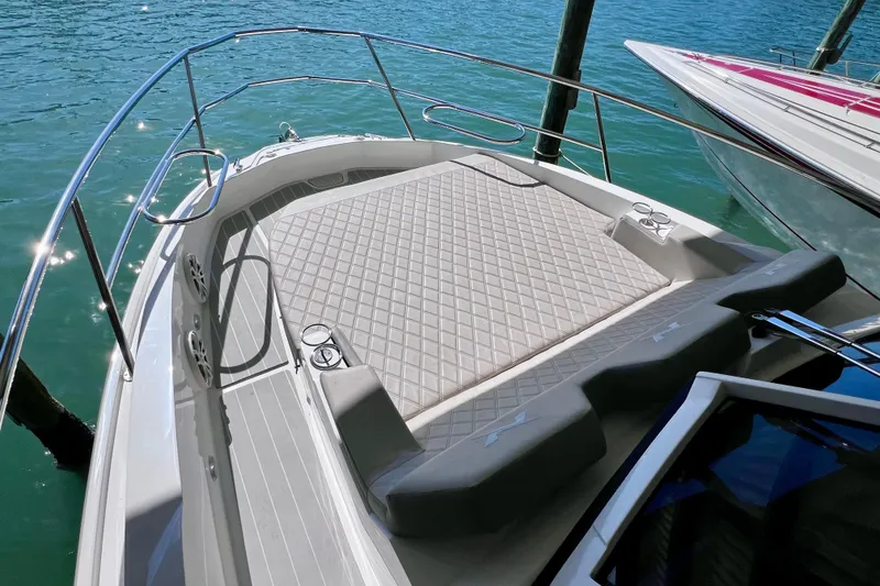 Slide: The Image of 2024 NX Boats 370 HT deck with cushioned seating, surrounded by clear blue water. - 58