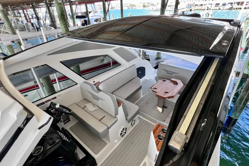 Slide: The Image of 2024 NX Boats 370 HT interior with seating and table, docked at marina. - 64