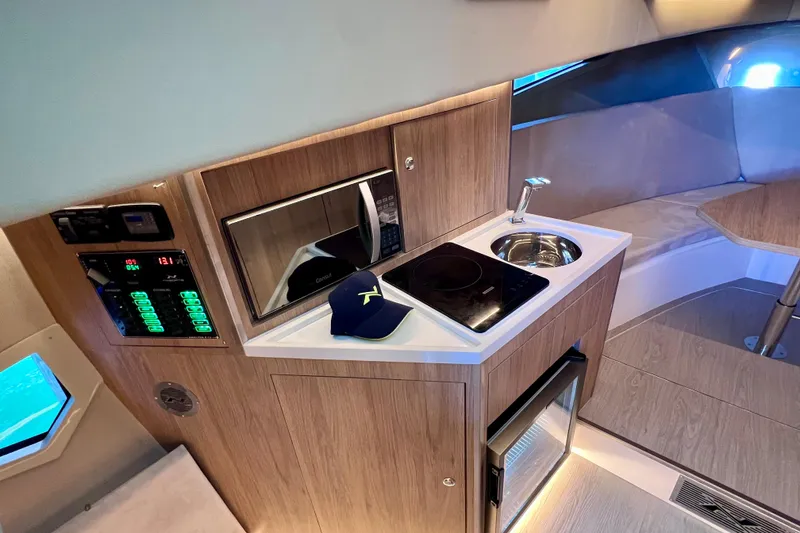 Slide: The Image of 2024 NX Boats 370 HT interior with kitchenette, featuring microwave, sink, and induction cooktop. - 67