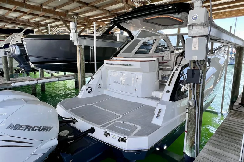 Slide: The Image of 2024 NX Boats 370 HT docked, showcasing sleek design and spacious deck area. - 8