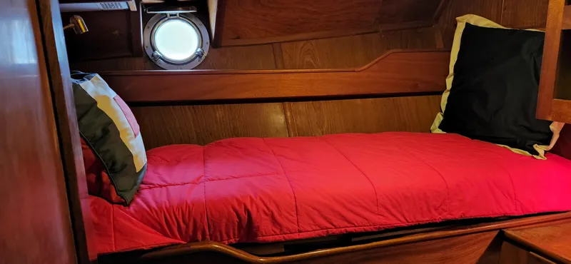 Slide: The Image of Cozy cabin bed in 1983 Thackwray Custom Pilothouse Motorsailer with red bedding and porthole. - 27
