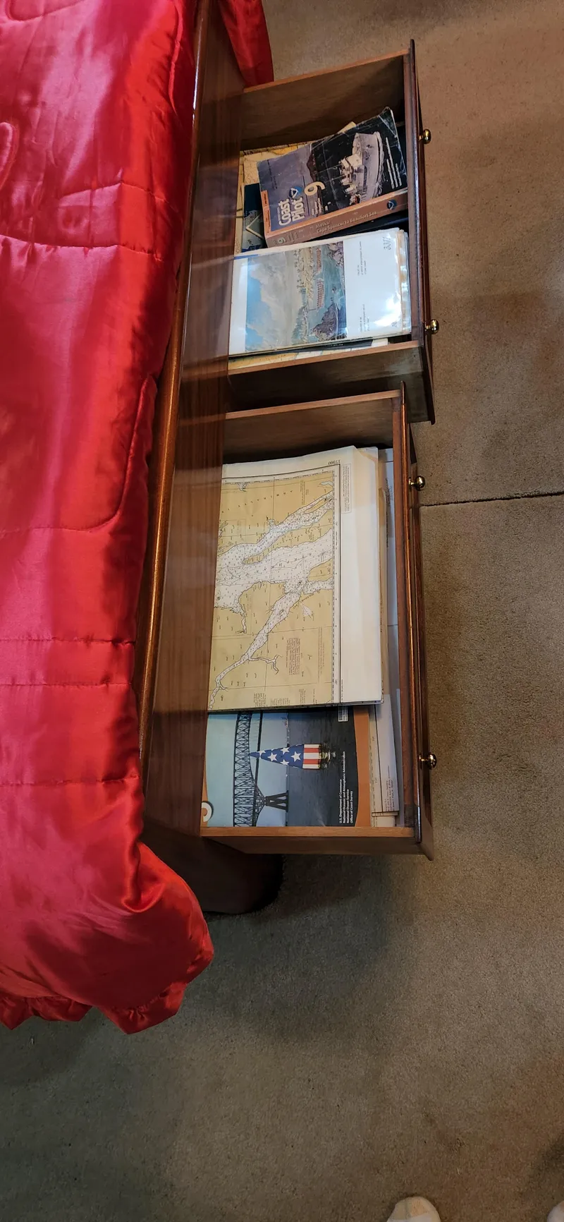Slide: The Image of Wooden drawer with maps and magazines beside a red bedspread. - 41