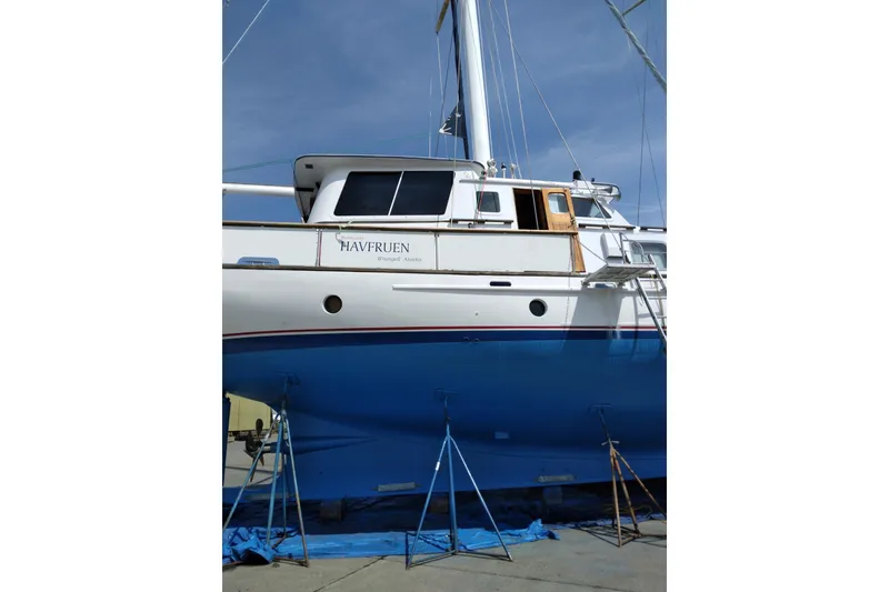 Slide: The Image of 1983 Thackwray Custom Pilothouse Motorsailer on stands, blue hull, white deck, clear sky. - 77