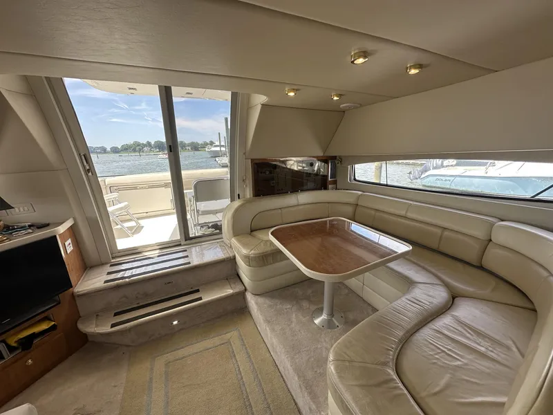 Slide: The Image of Luxurious 2002 Regal 3880 yacht interior with leather seating and wooden table, overlooking serene waters. - 18