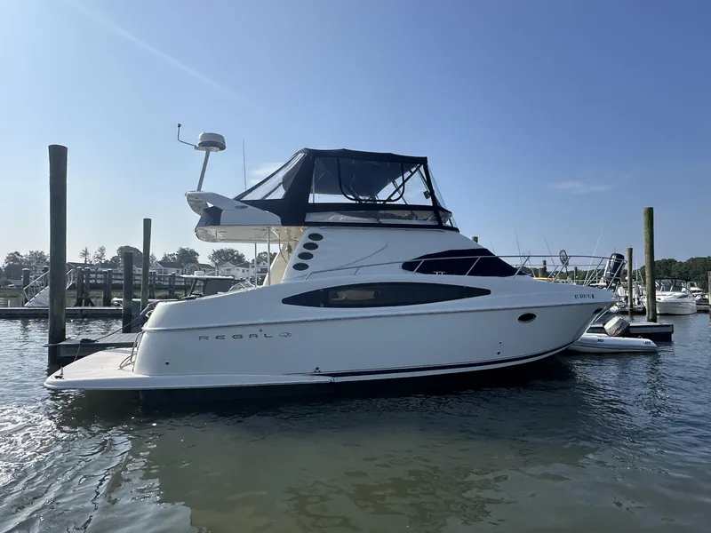 Slide: The Image of 2002 Regal 3880 yacht docked in a marina under clear blue skies. - 2