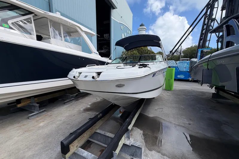 The Image of Four Winns HD3 boat on trailer, docked beside other vessels, under a blue sky. - 0