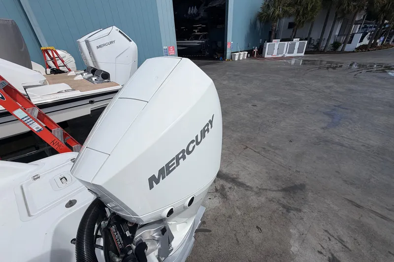 Slide: The Image of White Mercury outboard motor on a Four Winns HD3 boat, parked near a blue building. - 13