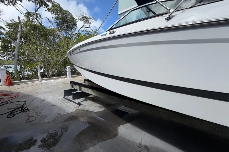 Slide: The Image of Four Winns HD3 boat on a lift, surrounded by trees and a clear sky. - 4