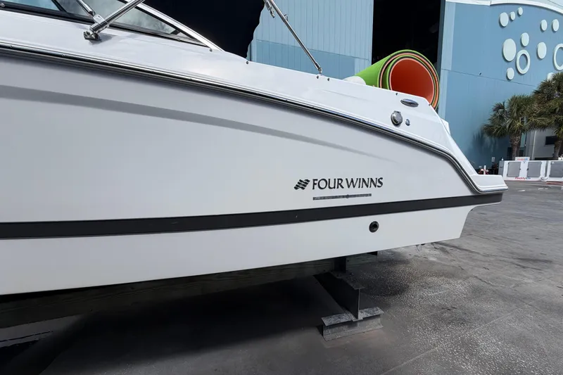 Slide: The Image of Four Winns HD3 boat side view, docked near a blue building with palm trees. - 6