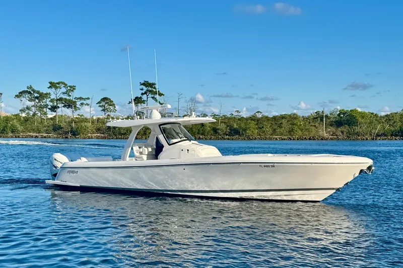 Slide: The Image of 2020 Intrepid 375 Nomad SE boat cruising on a calm, scenic waterway. - 2