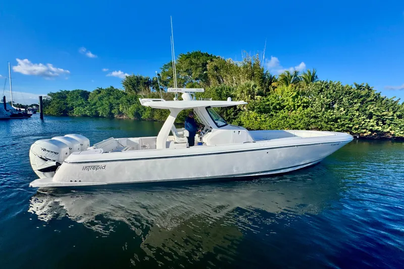 Slide: The Image of 2020 Intrepid 375 Nomad SE boat on calm water, surrounded by lush greenery. - 4