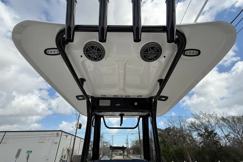 Slide: The Image of 2026 Sea Hunt BX 25 FS boat T-top with speakers and rod holders under a cloudy sky. - 12
