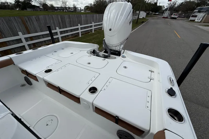 Slide: The Image of 2026 Sea Hunt BX 25 FS boat deck with storage compartments and motor, parked on a road. - 8