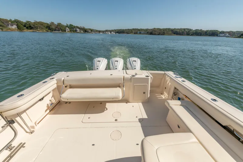 Slide: The Image of 2019 Grady-White Freedom 375 boat on calm water, showcasing spacious deck and triple engines. - 15