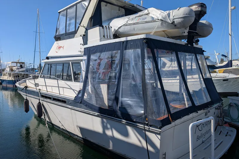 The Image of 1984 Californian 38 yacht docked at marina, featuring enclosed deck and inflatable boat on top. - 0