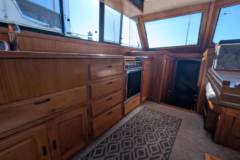 Slide: The Image of 1984 Californian 38 yacht interior with wooden cabinetry and stove, featuring large windows. - 6