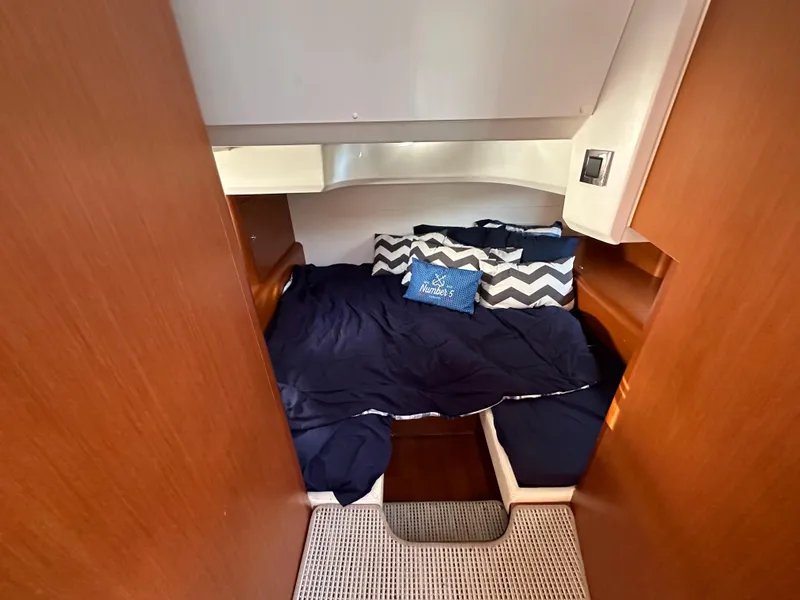 Slide: The Image of Cozy cabin interior of 2013 Beneteau Gran Turismo 38 with navy bedding and decorative pillows. - 14