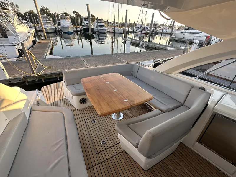 Slide: The Image of 2013 Beneteau Gran Turismo 38 yacht with spacious outdoor seating and wooden table at marina. - 3