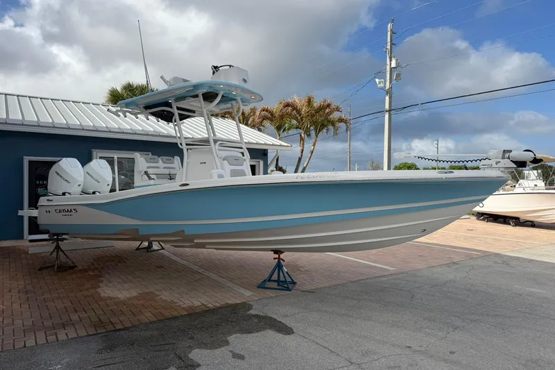Slide: The Image of 2022 Caymas 28 HB Twin boat displayed outdoors, featuring a sleek blue and white design. - 3