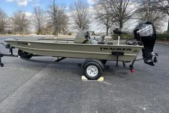 Slide: The Image of 2026 Tracker Grizzly 1754 SC boat on trailer, parked outdoors with trees in background. - 5