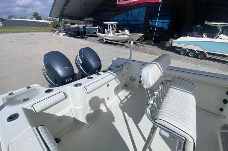 Slide: The Image of 2006 Sailfish 2360 CC boat with twin Yamaha 115 engines, docked near a marina. - 12