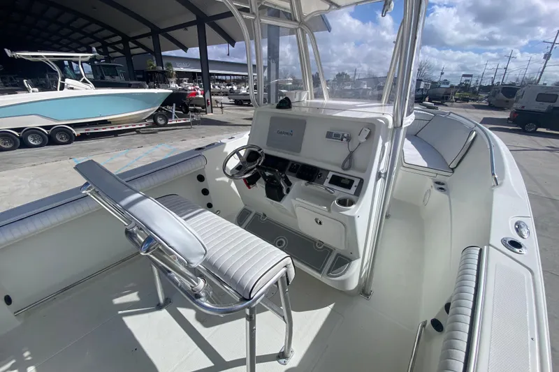 Slide: The Image of 2006 Sailfish 2360 CC boat interior with steering console and seating, docked under shelter. - 9