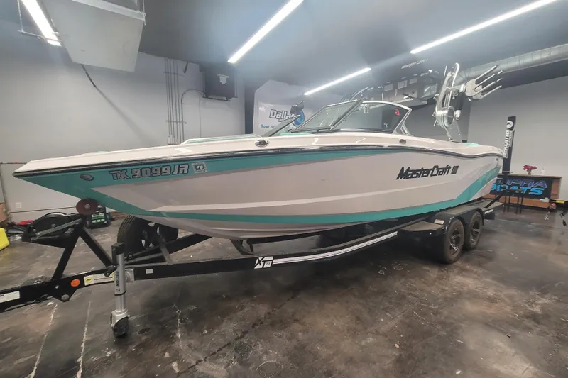 The Image of 2020 MasterCraft XT23 boat on trailer in indoor showroom. - 1