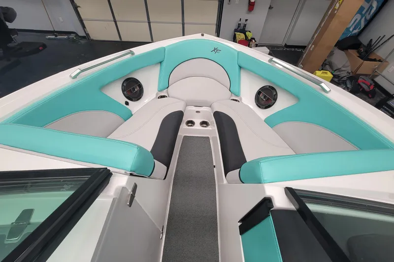 Slide: The Image of 2020 MasterCraft XT23 boat interior with teal and white seating, featuring speakers and cup holders. - 12