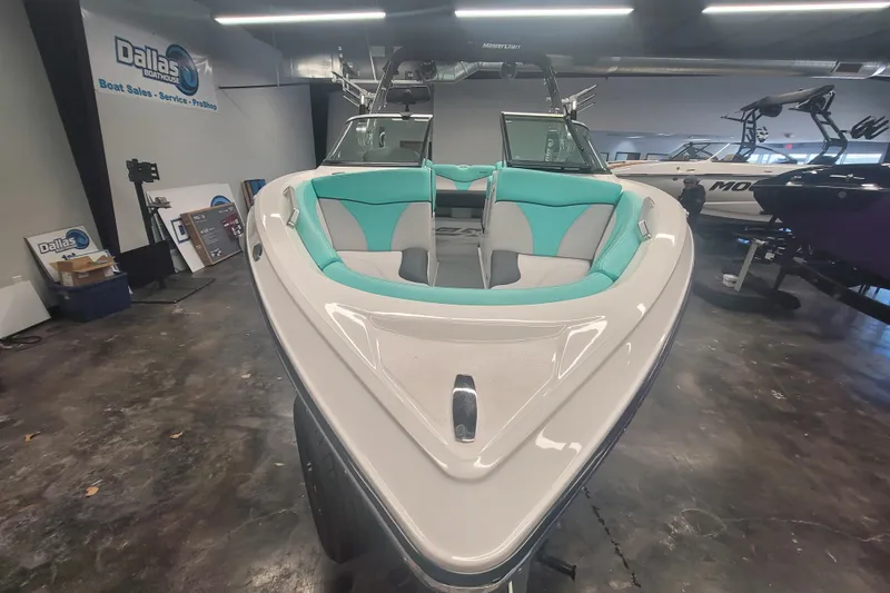 Slide: The Image of 2020 MasterCraft XT23 boat with teal and gray interior, displayed in showroom. - 3
