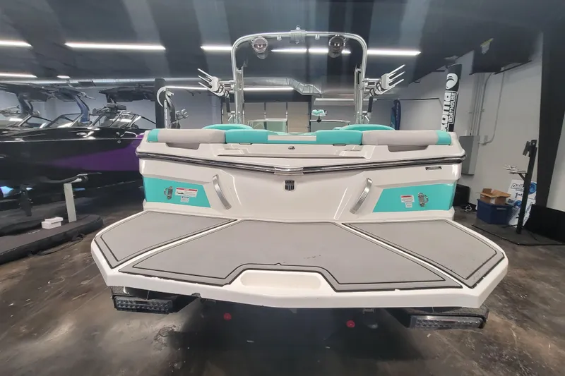Slide: The Image of 2020 MasterCraft XT23 boat in showroom, rear view with teal accents. - 7