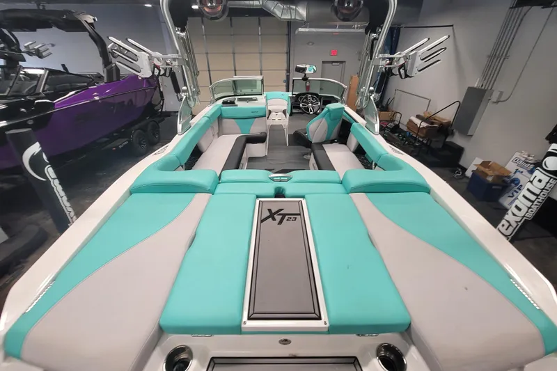 Slide: The Image of 2020 MasterCraft XT23 boat interior with teal and gray seating in a showroom. - 9