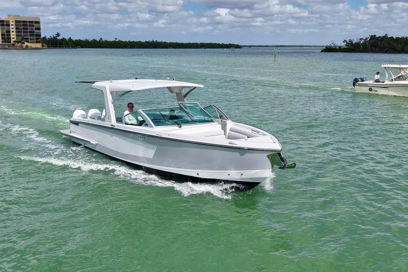 Slide: The Image of 2023 Aviara AV36 OB boat cruising on clear, green water under a partly cloudy sky. - 2