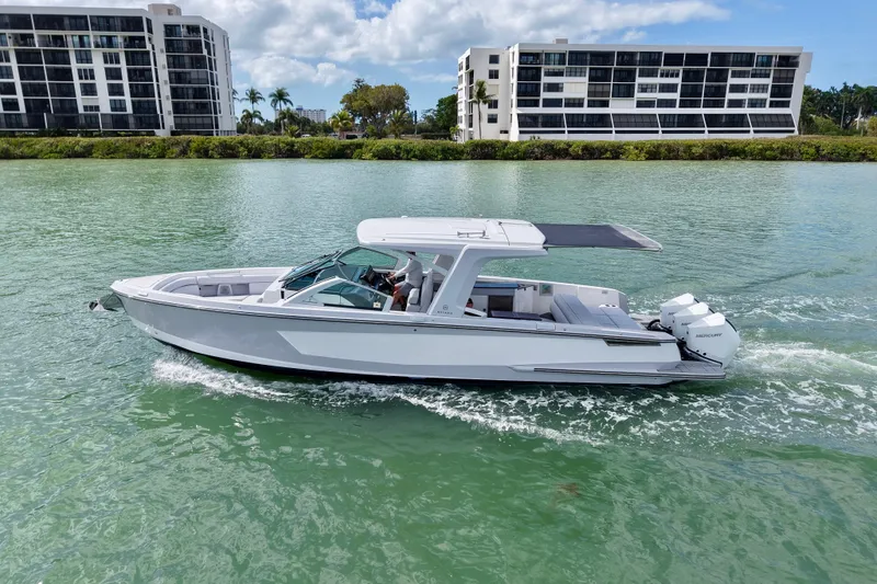 Slide: The Image of 2023 Aviara AV36 OB boat cruising on a scenic waterway with modern buildings in the background. - 5