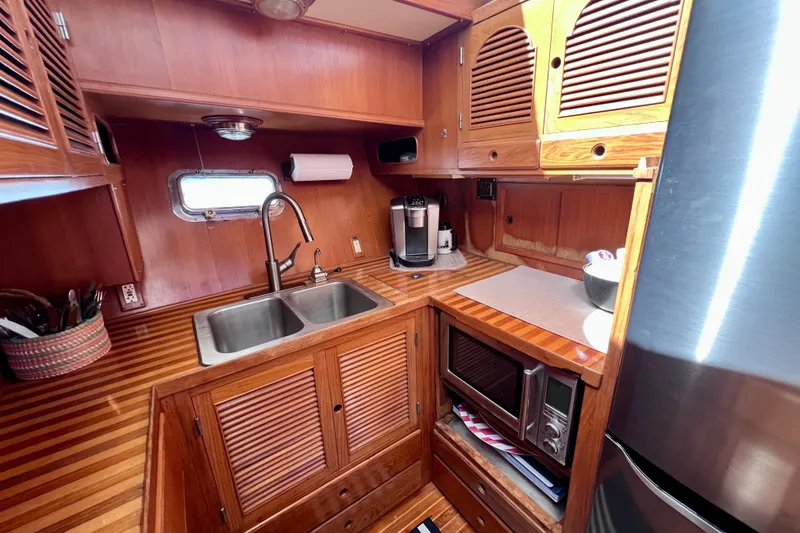 Slide: The Image of 1984 Kha Shing Spoiler yacht kitchen with wooden cabinetry, sink, and appliances. - 12