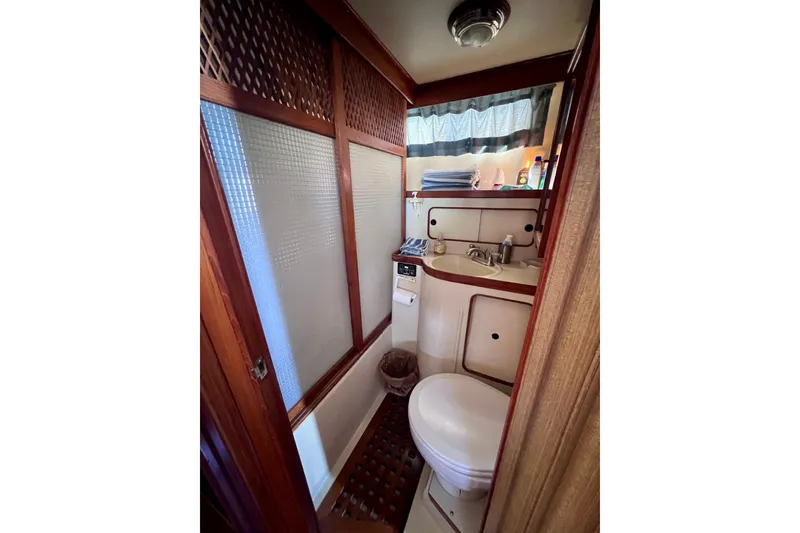 Slide: The Image of 1984 Kha Shing Spoiler Cockpit Motor Yacht bathroom with wooden accents and compact design. - 19