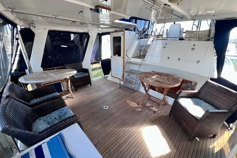 Slide: The Image of 1984 Kha Shing Spoiler Cockpit Motor Yacht interior with wicker seating and wooden tables. - 2