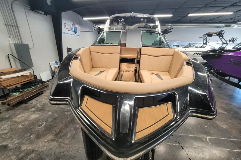 Slide: The Image of 2025 MasterCraft NXT23 boat with tan seating, showcased indoors. - 3