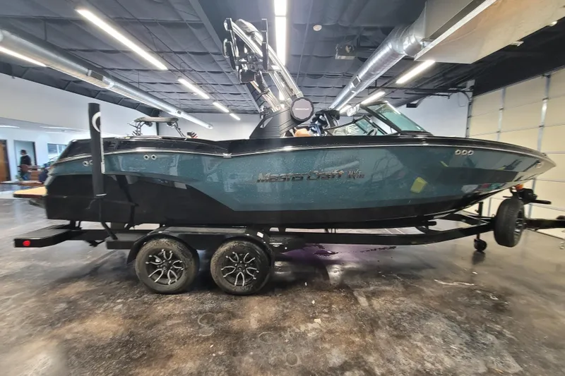 Slide: The Image of 2025 MasterCraft NXT23 boat on trailer in a showroom setting. - 5