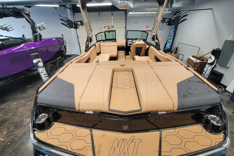 Slide: The Image of 2025 MasterCraft NXT23 boat interior with tan upholstery and modern design in showroom. - 7