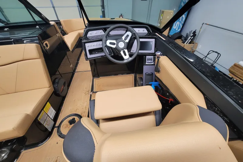 Slide: The Image of 2025 MasterCraft NXT23 boat interior with tan seating and modern dashboard. - 8