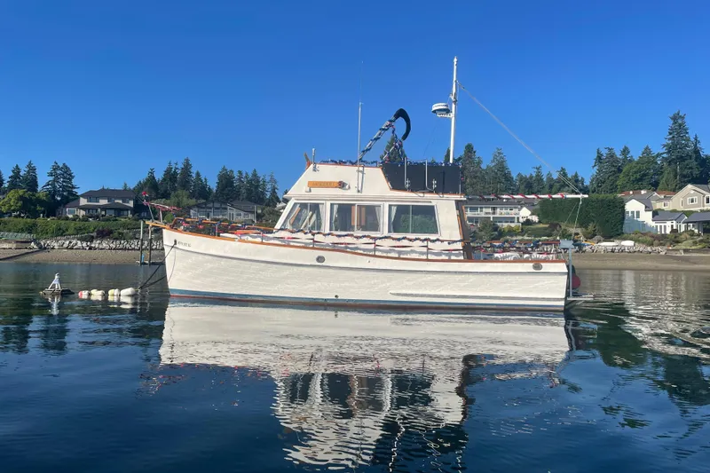 The Image of 1984 Grand Banks 32 Sedan boat on calm water, with scenic shoreline background. - 0