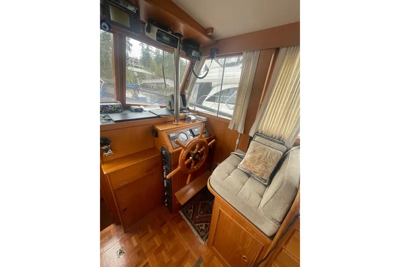 Slide: The Image of 1984 Grand Banks 32 Sedan interior with wooden helm, cushioned seating, and navigation equipment. - 11