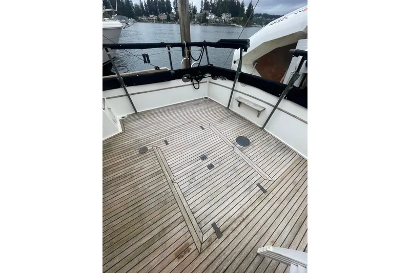 Slide: The Image of 1984 Grand Banks 32 Sedan boat deck with wooden flooring, docked by a serene waterfront. - 31