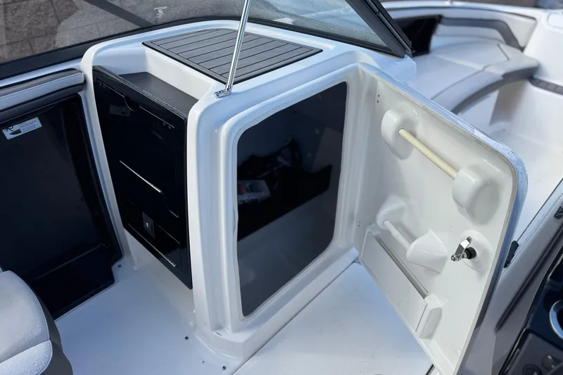 Slide: The Image of 2018 Yamaha Boats AR240 interior storage compartment with open door and seating area. - 21
