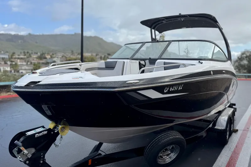 Slide: The Image of 2018 Yamaha Boats AR240 on trailer, sleek black design, parked outdoors with scenic background. - 3