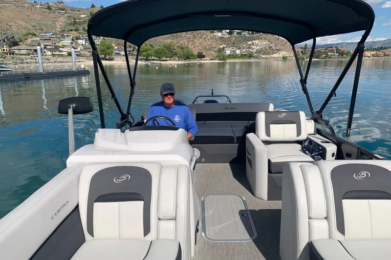 Slide: The Image of 2022 Barletta Corsa 25U pontoon boat on a scenic lake with a person at the helm. - 10